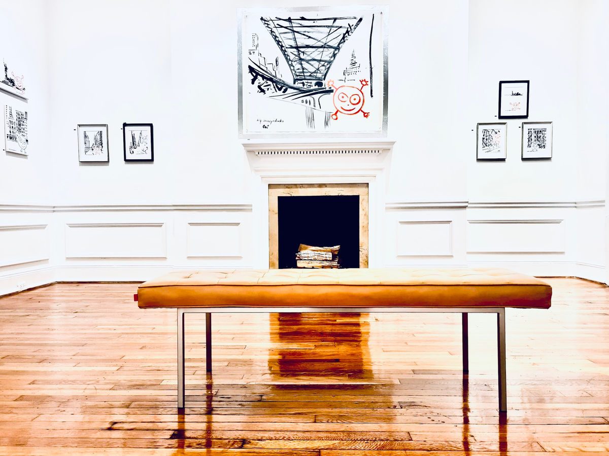New York gallery room with a wooden bench and small framed drawings on white walls