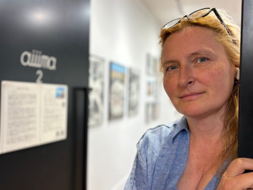 Zoia Skoropadenko at Aiiima Gallery with the gallery sign and exhibition space behind her
